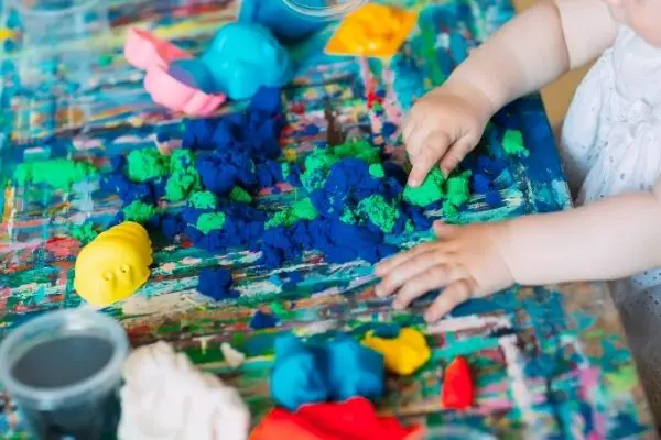 child playing with colorful kinetic sand at home