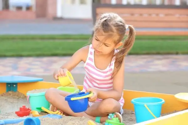 young girl playing on sandbox outdoors