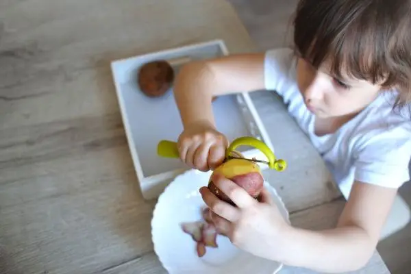 child peeling potatoes