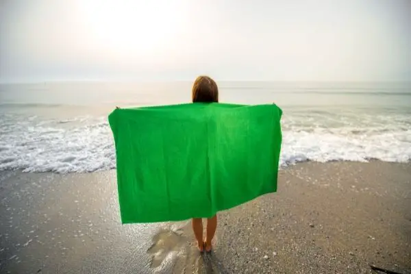 a woman holding a green towel at the beach