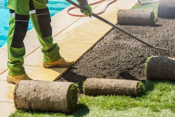 man taking care of lawn near a swimming pool