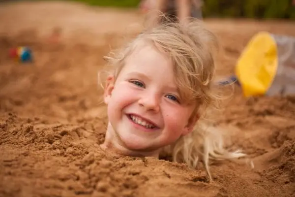 Young Girl With Naturally Curly Hair Buried In Sand