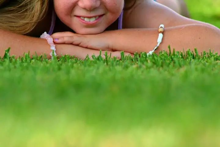 A Smiling Girl Is Laying On Lawn