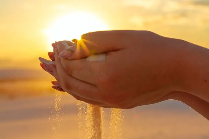 A Woman Is Holding Sand In Her Hands