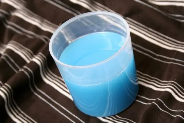 A Cup Of Liquid Detergent On Top Of Fabric