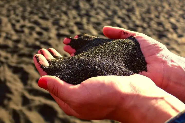 Man Is Holding Black Sand In Hands
