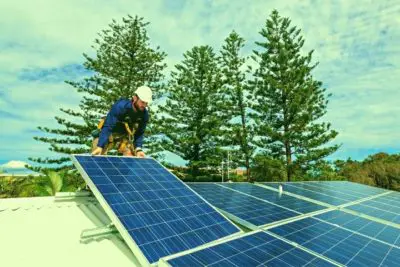 A photograph of a person installing solar panels on the roof