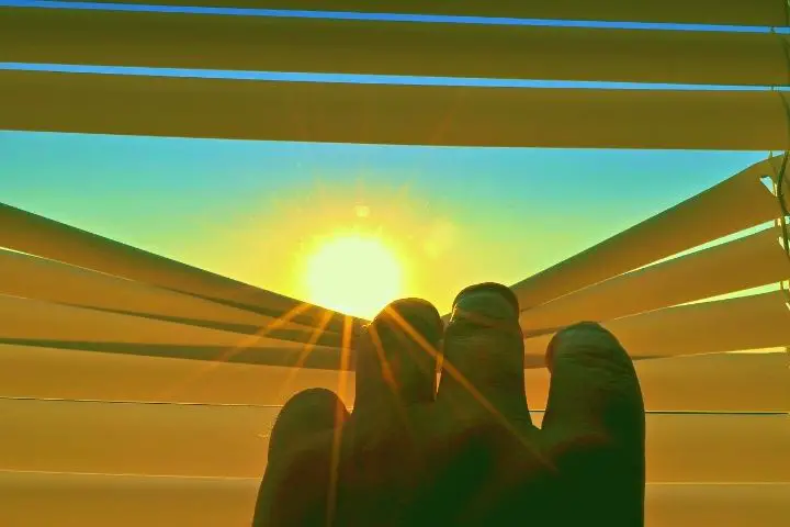 Man Opens The Blinds To See The Sun