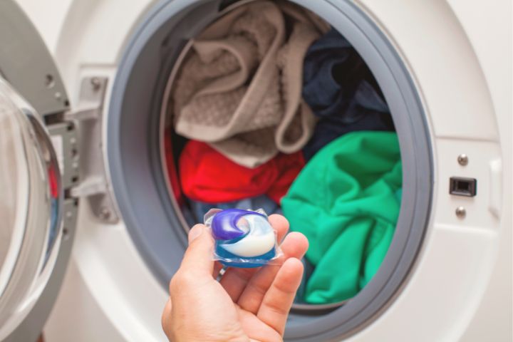 Detergent Pod In Mans Hand Near Washing Machine