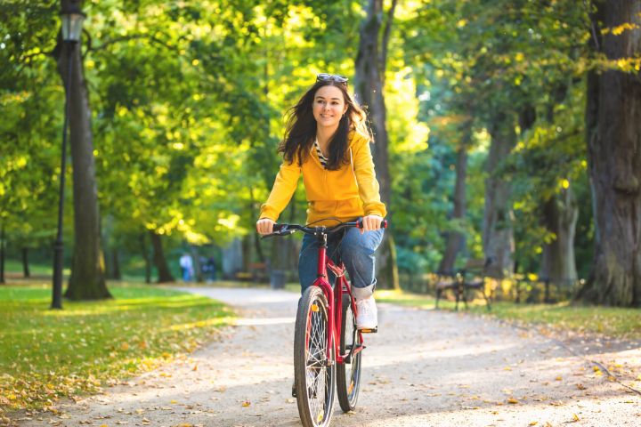 A Woman Rides A Bicycle In The Park