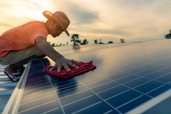 Man In Orange Hat Wiping Solar Panels With A Cloth