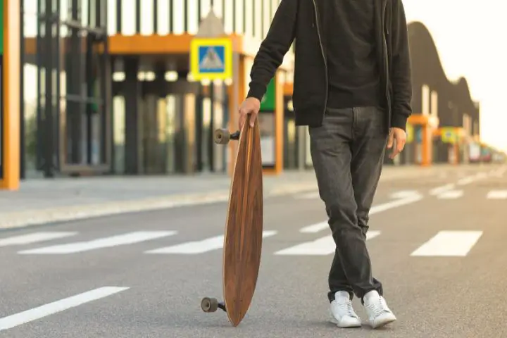 Man Stands On The Road And Holds Electric Skateboard