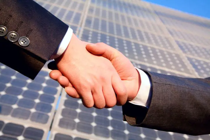 Shaking Hands In Front Of Solar Panels